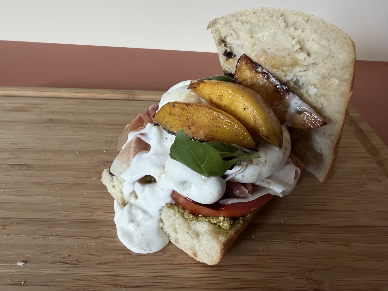 Belegd broodje parmaham met burrata die uitloopt en gebakken nectarines