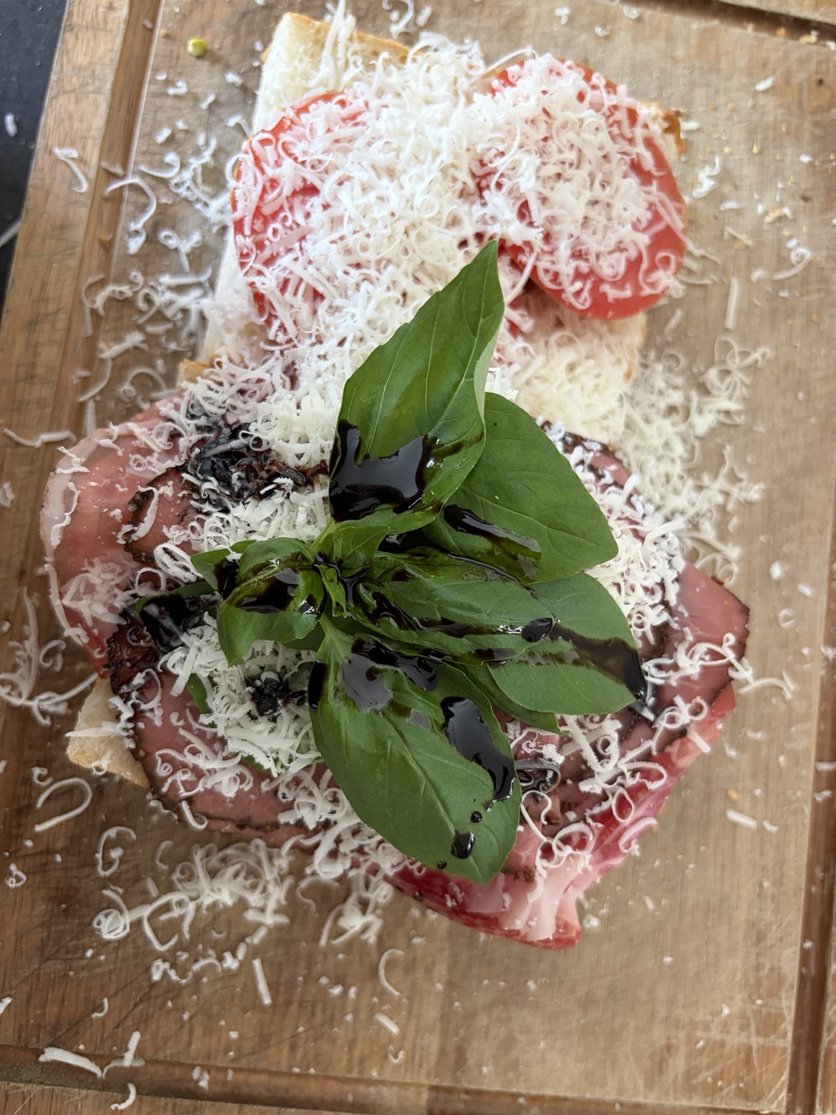 Broodje met heel veel geraspte pecorino en Parmezaanse kaas, met basilicum en balsamico bovenop