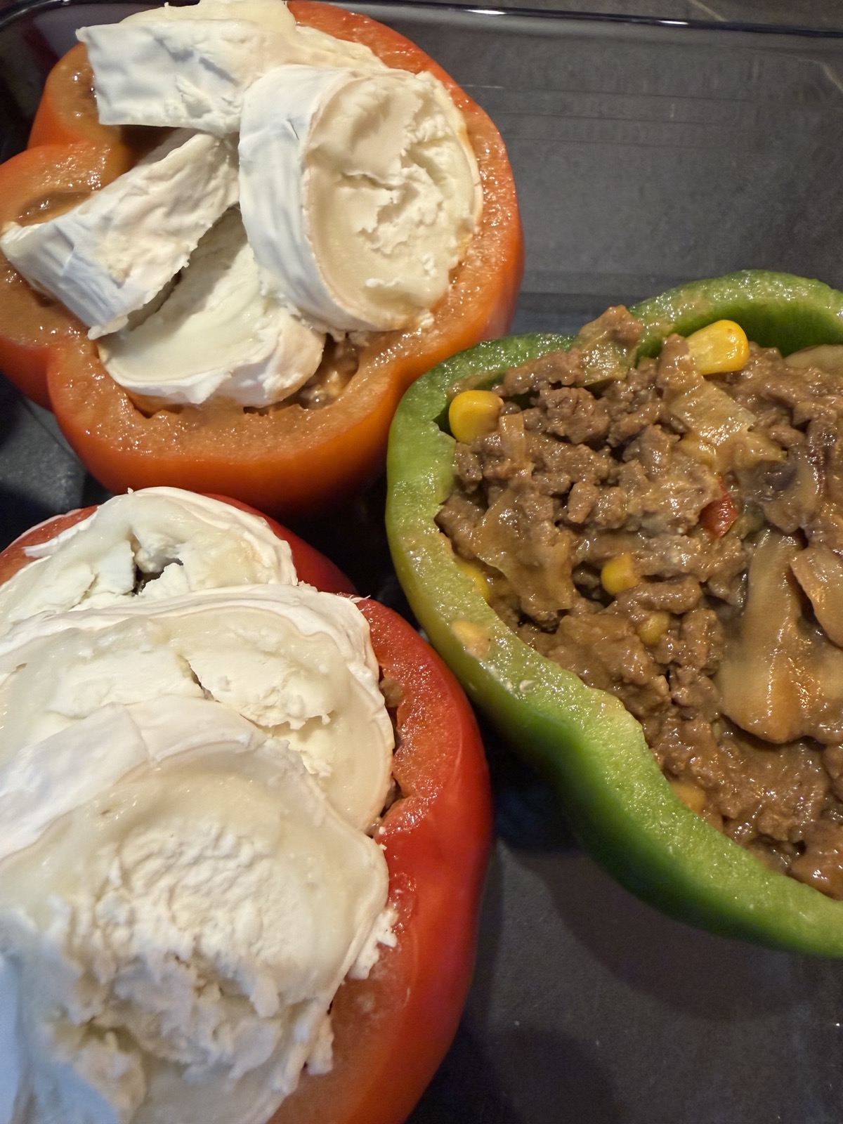 De gevulde paprika's met de plakjes geitenkaas erop, vlak voordat ze de oven in gaan