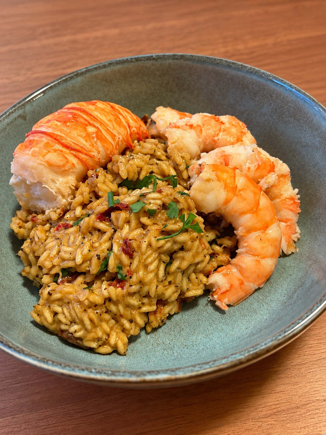 Een portie voor één persoon: een hele kreeftenstaart en een paar grote garnalen op de risotto — een flink bord